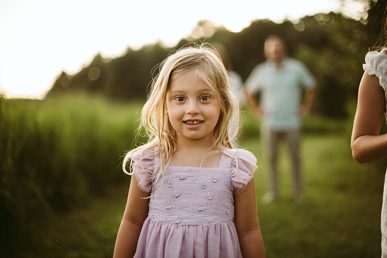 A candid moment of a family embracing in a golden-lit field of wildflowers